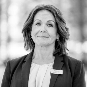 A woman with shoulder-length hair wearing a blazer and name tag stands outdoors, looking forward with a neutral expression. The name tag reads "Kalix, Kristina Blomqvist."